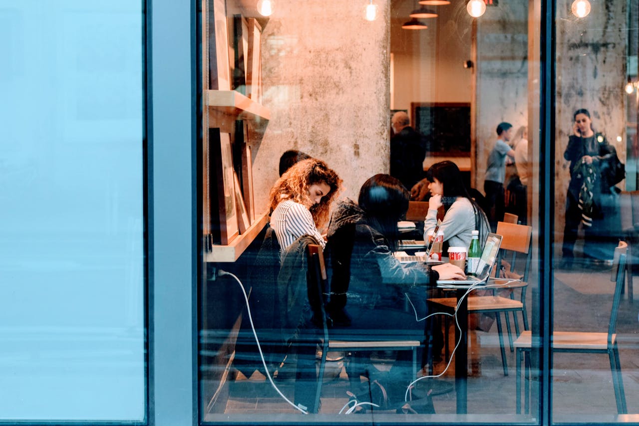 Group of adults working inside a stylish city cafe, showcasing modern work culture.